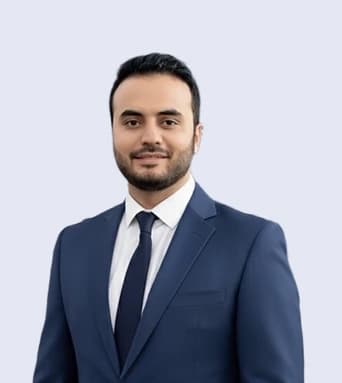 Haseeb Tariq, Founder and CEO of Report AI 365, smiling in a navy suit and dark tie against a pale grey background
