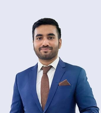 Wahab Tariq, Head of Product at Report AI 365, smiling in a blue suit with a brown tie and pocket square against a pale grey background